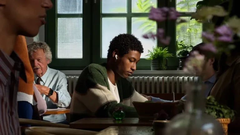 Person wearing AirPods 5 while working in a busy cafe