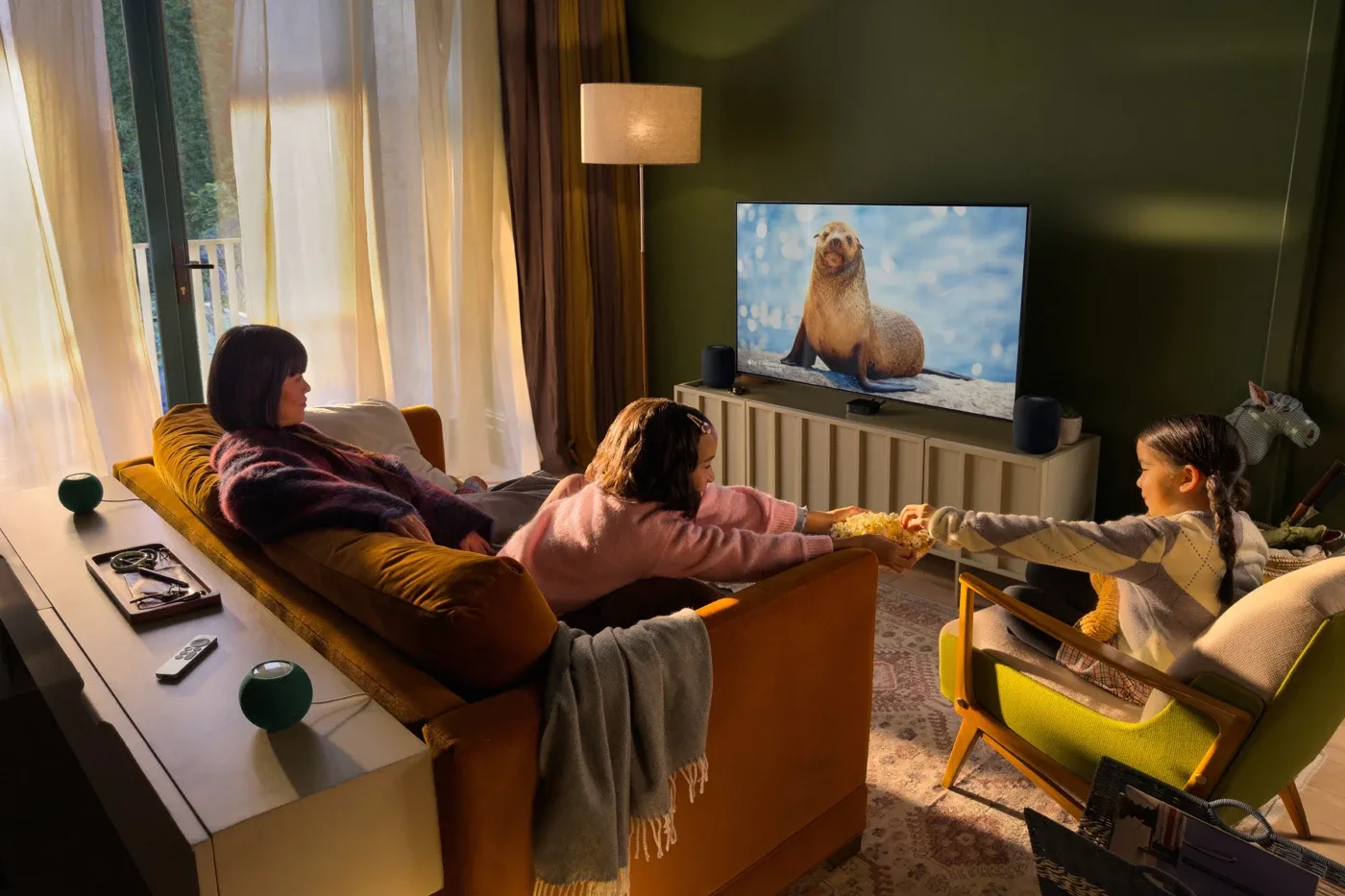 Official Apple room example with two HomePods at the television and two HomePod mini 2 speakers behind the seating