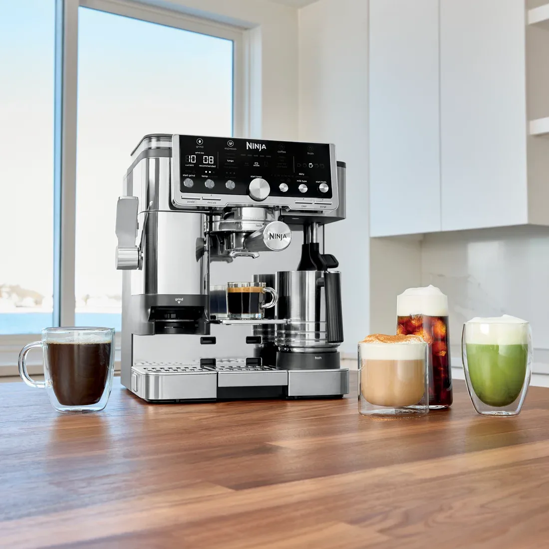 Ninja Luxe Café Pro ES701 on a kitchen counter with its XL milk jug and examples of milk and black coffee drinks